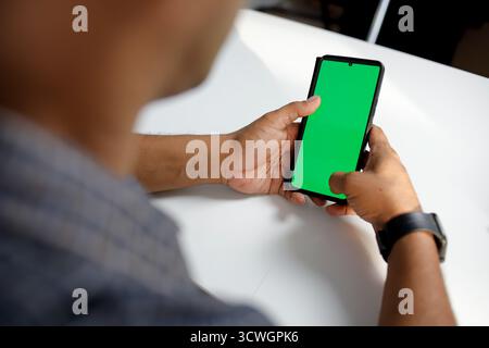 Cropped shot man using mockup mobile phone with green screen montage. Stock Photo
