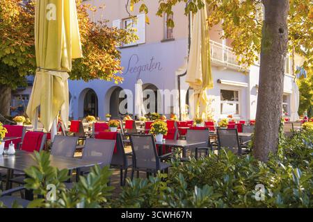 Cosy outdoor area of a cafe with red and black chairs, tables and large parasols in autumn light, Ueberlingen, Lake Constance, Germany Stock Photo