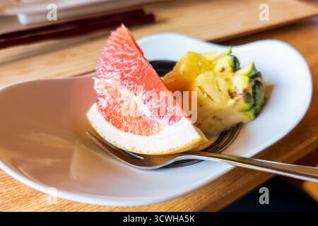 Slices of fresh red grapefruit and juicy pineapple on a modern white dessert plate Stock Photo