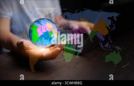 A businessman holding a digital globe with regional maps symbolizes regionalism, economic integration, and global connection in modern digital economy Stock Photo