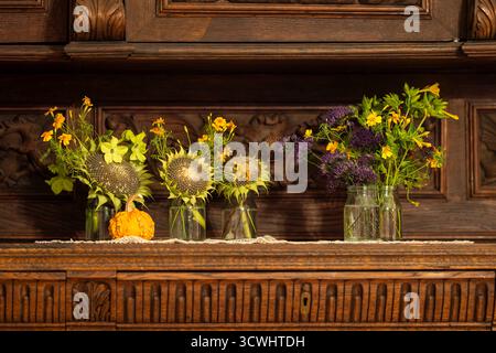 Still life with autumn flowers and decorative pumpkin. Autumn flowers in vase on wooden background. Stock Photo