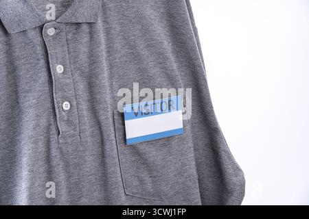 A gray shirt with visitor badge on pocket, featuring blue and white design. shirt is casual polo style, emphasizing professional relaxed appearance Stock Photo