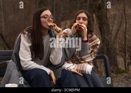 Two young women eating marshmallows near the campfire. Stock Photo