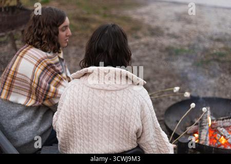 two young women roasting marshmallows over a campfire Stock Photo
