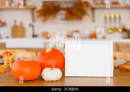 Bright pumpkins and blank cardboard on wooden table in cozy kitchen background, perfect for autumn, fall or Halloween and Thanksgiving decor. Mockup, Stock Photo