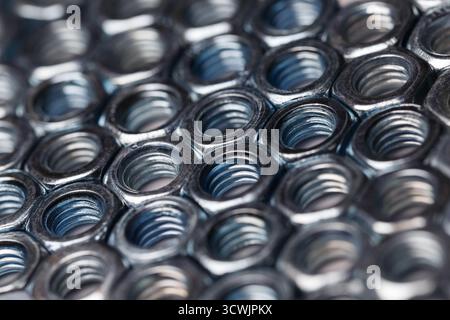 Shiny metal nuts arranged in a precise order. Diagonal composition with selective focus. Stock Photo