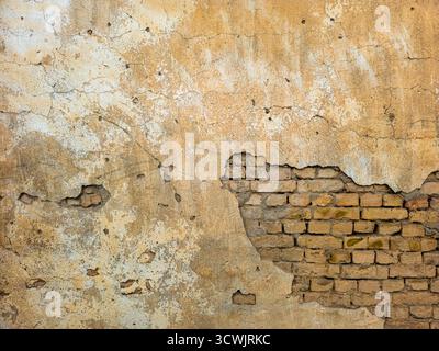 Old brick wall with peeling plaster and exposed bricks Stock Photo