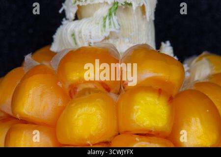 Macro shot of yellow corn kernels against a dark background, with white husks in the background. Stock Photo
