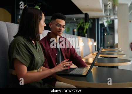 Young businesswoman and businesswoman discussing with laptop at desk in office lounge Stock Photo