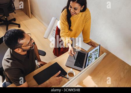 Young male and female architects working together reviewing architectural designs on a laptop. Collaborative professional environment showcasing teamw Stock Photo