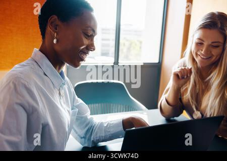 Two young women collaborating on a project, engaging ideas and teamwork in an office. Stock Photo