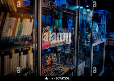 Retro Japanese video games, including Donkey Kong 64, are displayed inside a glass case at a gaming venue Stock Photo
