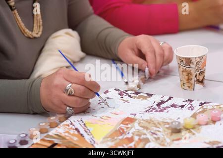 Woman's hand drawing on numbered canvas painting by numbers. Creative hobby Stock Photo