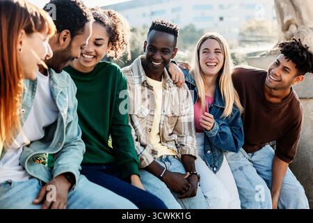Group of millennial friends sitting outdoors in the city Stock Photo