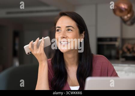 Happy Latin freelancer woman listening to voice message on smartphone Stock Photo