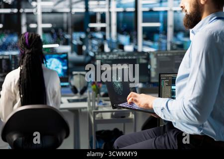 Network engineers in data center troubleshooting server connectivity issues using AI. Technicians in server room auditing systems for vulnerabilities using artificial intelligence Stock Photo