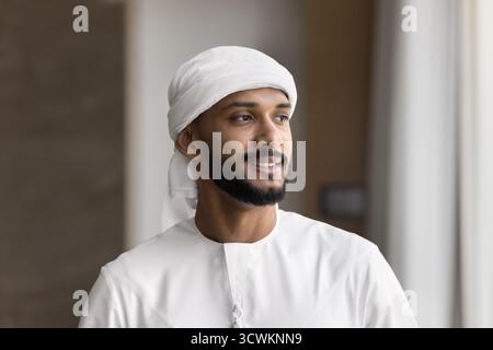 Young Arabian man wearing Muslim dress look aside with smile Stock Photo