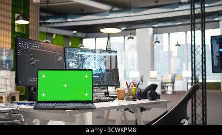 Green screen laptop and AI algorithms running on computer monitors in empty startup workspace deploying machine learning models. Mockup notebook and artificial intelligence coding platform in office Stock Photo