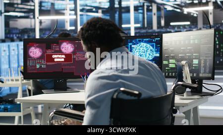 Overworked man in wheelchair upset by error warning popup while looking at server hub AI analytics metrics. Data center worker with disability irked by malfunction while using node tree tool, camera B Stock Photo
