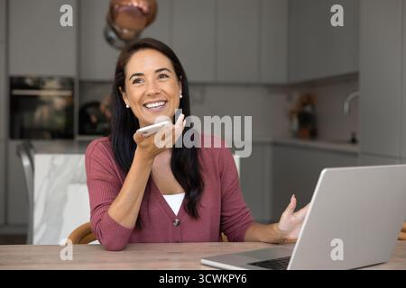 Happy beautiful Latin manager woman talking on cell on speaker Stock Photo