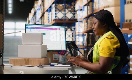 Female warehouse clerk registering barcodes for packages, scanning the shipping labels and awb tags on cardboard boxes. Fulfillment center distribution operations for e-commerce. Camera B. Stock Photo