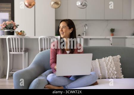 Happy young Hispanic freelancer woman using laptop at home Stock Photo