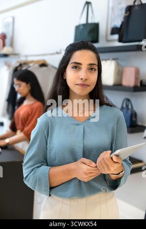 Positive young Hispanic retail professional woman posing in store showroom Stock Photo