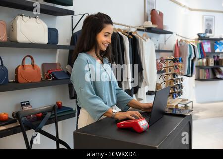 Positive Latin retail fashion store manager woman working in showroom Stock Photo