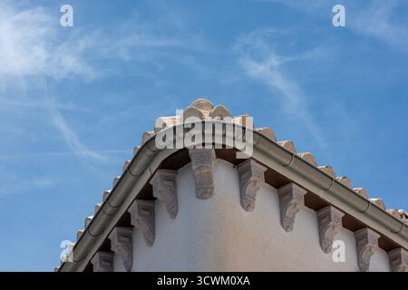 The corner corniceof a building located in souther Spain with blue skies and light cumulus clouds in the background. Stock Photo