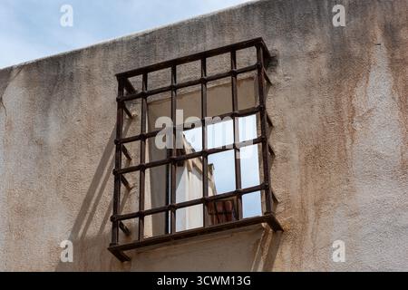 A metal grate protects an empty window space on a dilapidated building in Souther Spain. Stock Photo