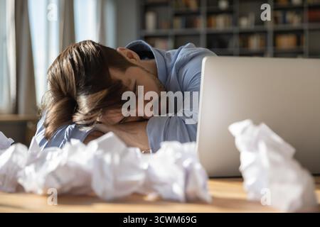 Stressed tired young man freelance author sleeping on office desk Stock Photo