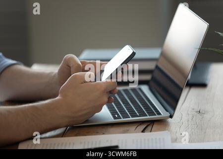 Closeup male hands using phone laptop books documents at desk Stock Photo
