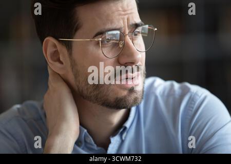 Nervous concerned young man rubbing back of neck in anxiety Stock Photo