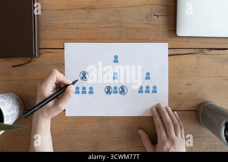 Closeup male hand crossing out figures from structure on paper Stock Photo