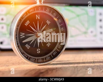 A close-up shot of a person holding a vintage-style compass with a metallic finish and clear markings for cardinal directions (N, S, E, W) and degree Stock Photo