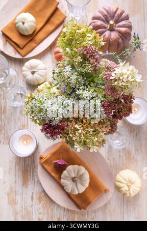 Beautiful bouquet of autumn flowers in pumpkin on festive dining table Stock Photo
