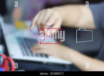 A holographic image of an envelope with the number 1 in the center, symbolizing a new email notification, is superimposed over an image of a person wo Stock Photo