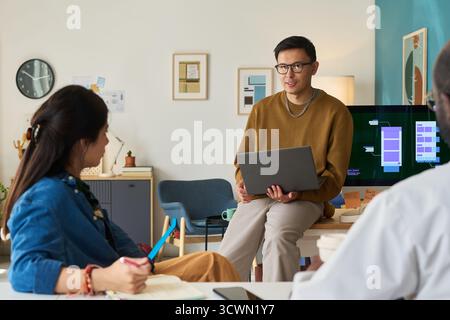 Man Explaining Project to Diverse Colleagues in Office Stock Photo