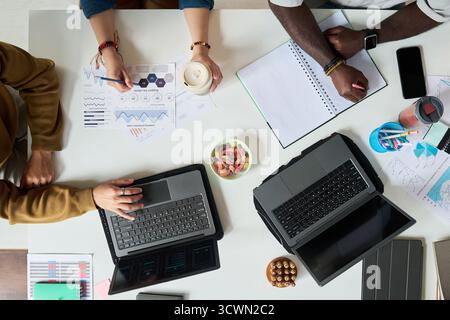 Diverse Adults Collaborating on Business Project with Laptops and Charts Stock Photo