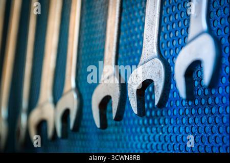 Metal wrenches organized on a blue perforated panel, ready for repair work Stock Photo