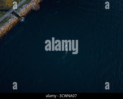 Aerial view of boats cutting through the calm, dark blue baltic sea near the rocky coastline, Nyhamnen, Malmo, Sweden. Stock Photo