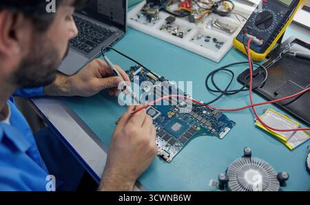 Technician man worker is focused on working with a motherboard Stock Photo