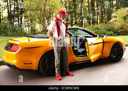 Stylish senior man getting out of modern cabriolet outdoors Stock Photo