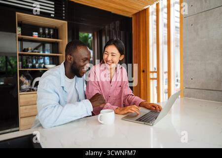 Multicultural couple working remotely, planning finances and investments. Digital nomad lifestyle Stock Photo
