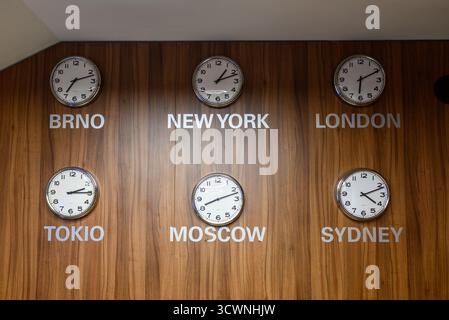 A wall with six clocks showing different times for various cities including New York, London, Tokyo, Moscow, Sydney and Brno Stock Photo
