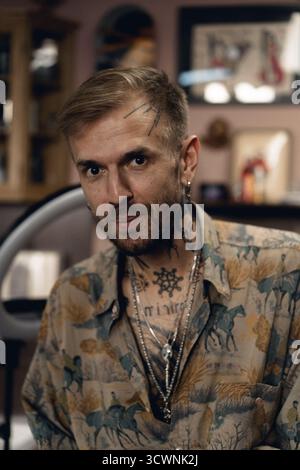 Man with tattoos and a stylish shirt looking confidently at the camera Stock Photo