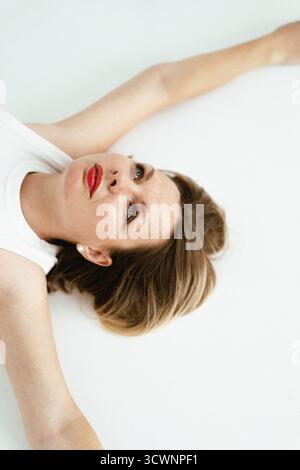 Portrait of a woman lying on a white surface looking at the camera Stock Photo