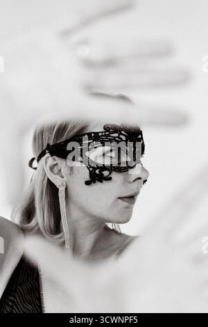 Woman wearing ornate black lace masquerade mask, black and white Stock Photo
