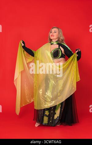 Happy Caucasian woman fashion model attired in black and yellow dance stage outfit - pareo, bra top, bolero, maxi skirt and she is not wearing any foo Stock Photo