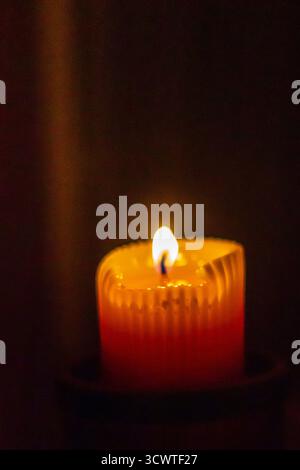 Warm Candle Flame Casts Soft Glow Across Dark Room for Cozy Nighttime Ambience Stock Photo